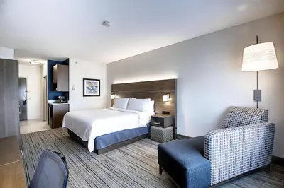 a hotel room with a bed and a chair at Holiday Inn Express Airport Calgary by IHG in Calgary