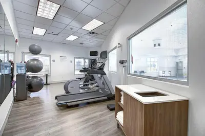 a gym with a treadmill and ellipticals in a room at Holiday Inn Express Airport Calgary by IHG in Calgary