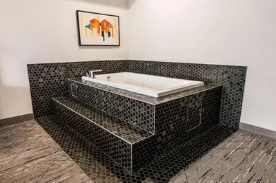 a bathroom with a bath tub with black tile at Holiday Inn Express Calgary South by IHG in Calgary