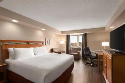 a hotel room with a bed and a desk and a television at Royal Hotel West Edmonton, Trademark Collection by Wyndham in Edmonton