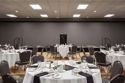 a room full of tables and chairs with white tablecloths at Royal Hotel West Edmonton, Trademark Collection by Wyndham in Edmonton