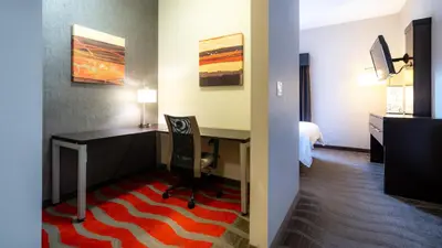 a hotel room with a desk and a bedroom at Holiday Inn Express Hotel & Suites - Edmonton International Airport by IHG in Nisku
