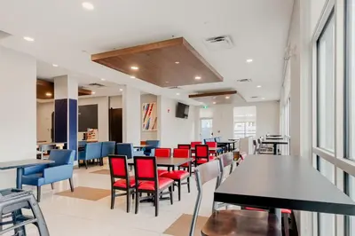 a dining room with tables and red chairs at Holiday Inn Express Hotel & Suites-Edmonton South by IHG in Edmonton