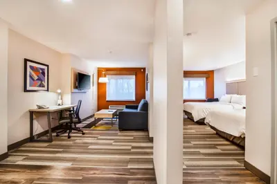 a hotel room with two beds and a desk at Holiday Inn Express & Suites Langley by IHG in Langley