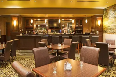 a restaurant with tables and a bar at Holiday Inn Hotel & Suites-West Edmonton by IHG in Edmonton