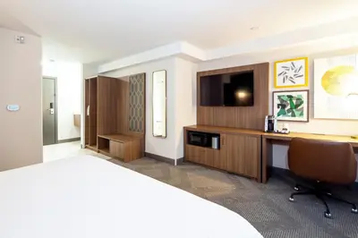 a hotel room with a bed and a desk with a television at Holiday Inn Hinton by IHG in Hinton