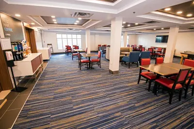 a dining area with tables and chairs in a cafeteria at Holiday Inn Express Hotel & Suites-Hinton by IHG in Hinton