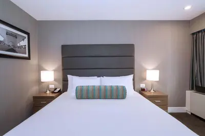 a bedroom with a large white bed with two lamps at Sandman Signature Calgary Downtown Hotel in Calgary