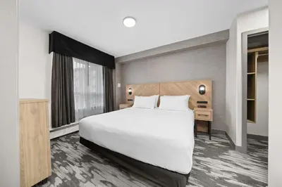 a hotel room with a large white bed and a desk at Sandman Hotel Calgary Airport in Calgary