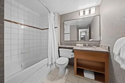 a bathroom with a toilet and a tub and a sink at Sandman Hotel Calgary Airport in Calgary