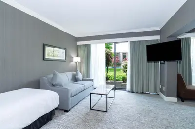 a hotel room with a bed and a couch and a tv at Sandman Signature Vancouver Airport Hotel & Resort in Richmond
