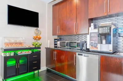 a kitchen with wooden cabinets and a counter with a microwave at Sandman Signature Vancouver Airport Hotel & Resort in Richmond