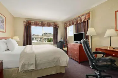 a hotel room with a bed and a desk and a chair at Days Inn by Wyndham Vancouver Airport in Richmond