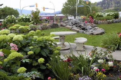 a park with a bench in a garden with flowers at Dilworth Inn Kelowna in Kelowna