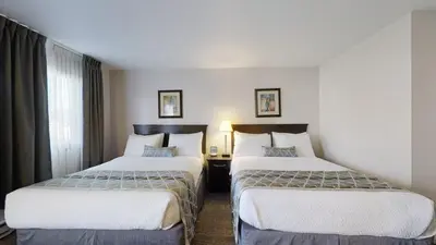a hotel room with two beds and a window at Dilworth Inn Kelowna in Kelowna