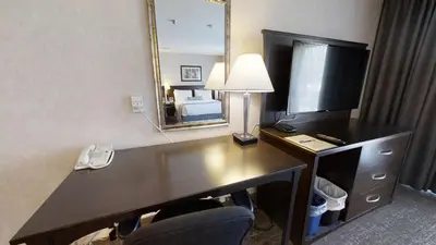 a hotel room with a desk with a computer and a mirror at Dilworth Inn Kelowna in Kelowna