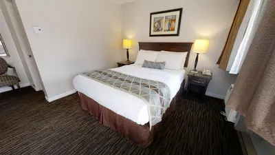 a hotel room with a bed and two lamps at Recreation Inn and Suites Kelowna in Kelowna