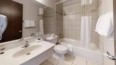 a bathroom with a sink and a toilet and a bath tub at Recreation Inn and Suites Kelowna in Kelowna