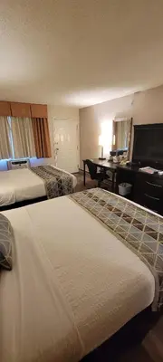 a hotel room with two beds and a desk at Recreation Inn and Suites Kelowna in Kelowna