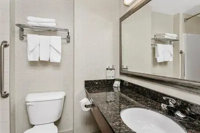 a bathroom with a toilet and a sink and a mirror at Holiday Inn & Suites Lloydminster by IHG in Lloydminster