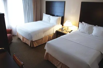 a hotel room with two beds and a chair at iHOTEL & Conference Centre Red Deer in Red Deer