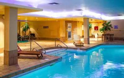 a hotel pool with two chairs and a table at iHOTEL & Conference Centre Red Deer in Red Deer