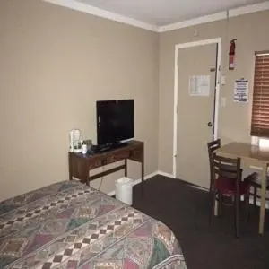 a hotel room with a bed and a desk with a television at Bluebird Motel in Port Alberni