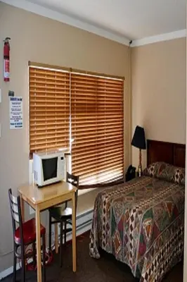 a bedroom with a bed and a desk with a computer on it at Bluebird Motel in Port Alberni