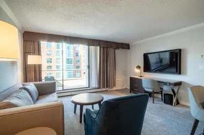 a hotel room with a couch and a desk and a television at La Grande Residence at the Sutton Place Hotel in Vancouver