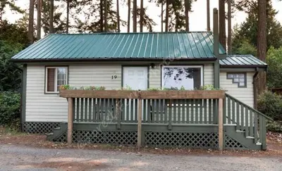a small white house with a green tin roof at The Surf Lodge and Pub in Gabriola