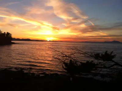 a sunset over a body of water with the sun setting at The Surf Lodge and Pub in Gabriola