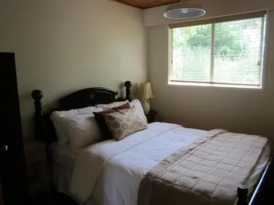 a bedroom with a bed with white sheets and a window at The Surf Lodge and Pub in Gabriola