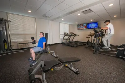 two men working out in a gym with machines at Encore Suites by Service Plus Inns in Grande Prairie