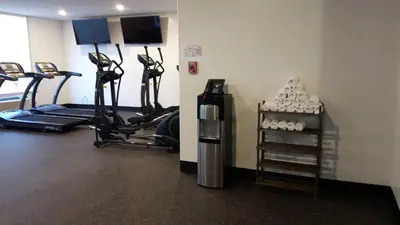 a gym with several treadmills and cardio machines at Encore Suites by Service Plus Inns in Grande Prairie