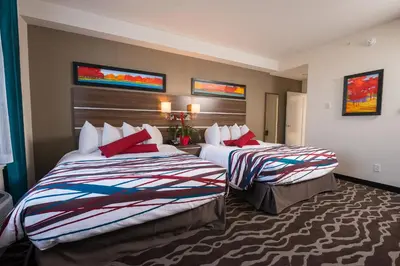 a hotel room with two beds with red pillows at Encore Suites by Service Plus Inns in Grande Prairie