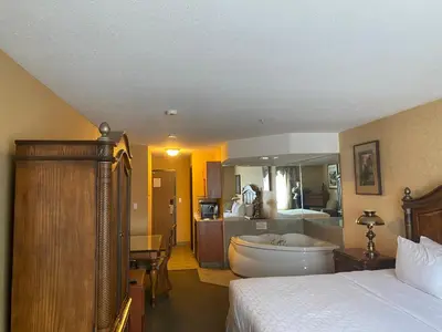 a bedroom with a bed and a tub and a bathroom at Merit Hotel & Suites in Fort McMurray