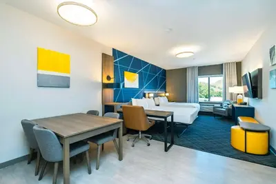 a hotel room with a bed and a desk and a table at Comfort Suites Kelowna in Kelowna