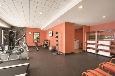 a gym with exercise equipment in a room with orange walls at Home2 Suites by Hilton Fort St. John in Fort Saint John