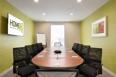 a conference room with a wooden table and black chairs at Home2 Suites by Hilton Fort St. John in Fort Saint John