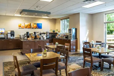 a restaurant with tables and chairs and a kitchen at Comfort Inn & Suites in Surrey