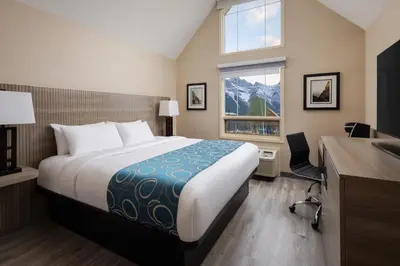 a hotel room with a bed and a desk and a window at Grande Rockies Resort-Bellstar Hotels & Resorts in Canmore