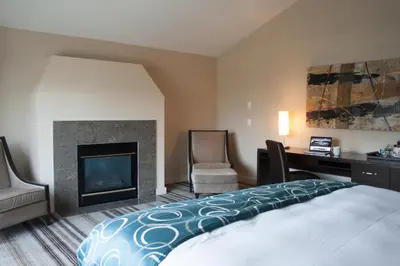 a bedroom with a bed and a desk and a fireplace at Grande Rockies Resort-Bellstar Hotels & Resorts in Canmore