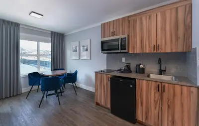 a kitchen with wooden cabinets and a table with chairs at Prestige Kamloops Hotel in Kamloops