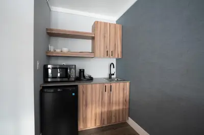 a kitchen with a black refrigerator and wooden cabinets at Prestige Kamloops Hotel in Kamloops