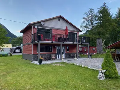 a red house with a balcony and a yard at Guesthouse Austria in Stewart