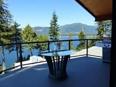 a table on a balcony with a view of the water at Fish Tales Cottage in Port Renfrew
