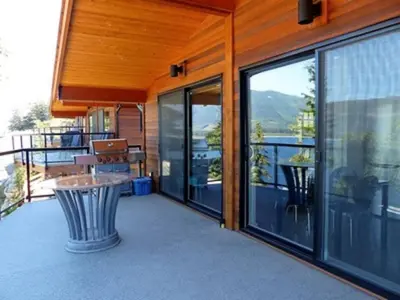a balcony of a house with a table and windows at Fish Tales Cottage in Port Renfrew