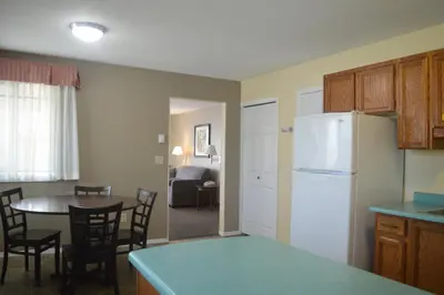 a kitchen with a table and a white refrigerator at Siesta Suites in Kelowna