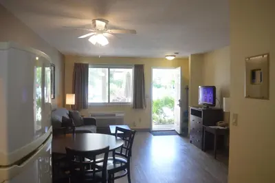 a living room with a table and chairs and a television at Siesta Suites in Kelowna