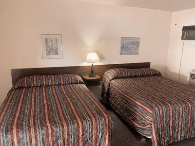 a hotel room with two beds and a lamp at Evergreen Motel in Princeton
